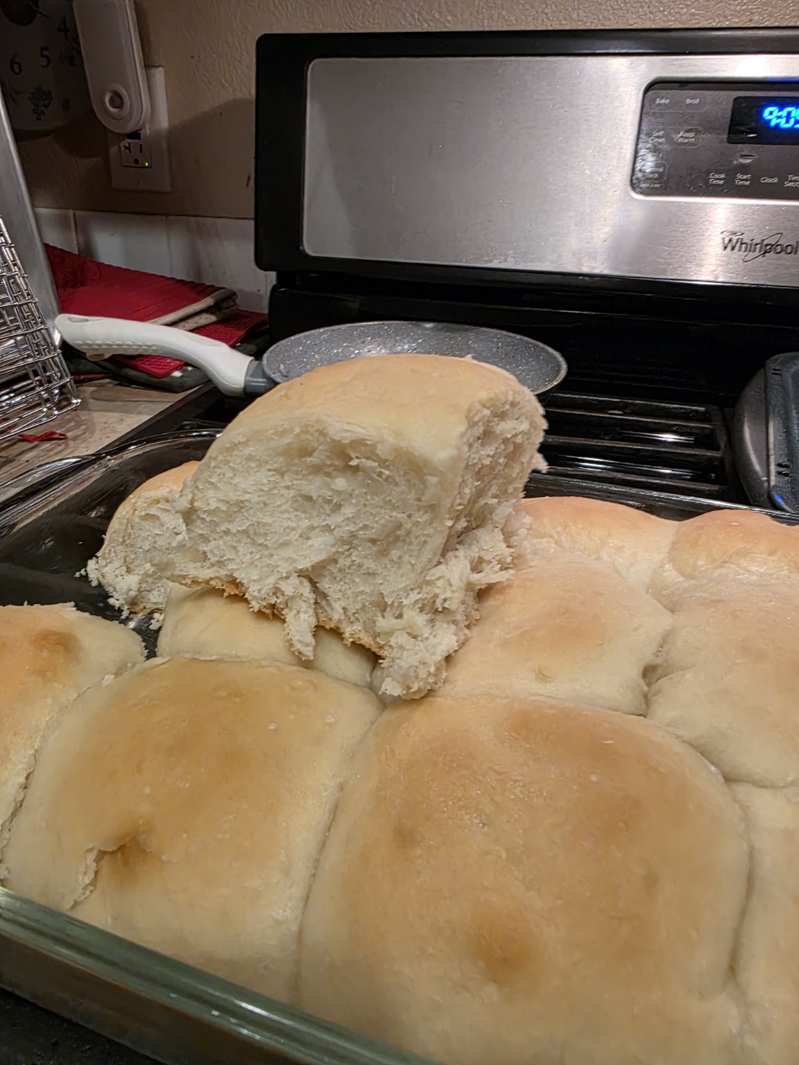 A sourdough dinner roll pulled apart above the pan